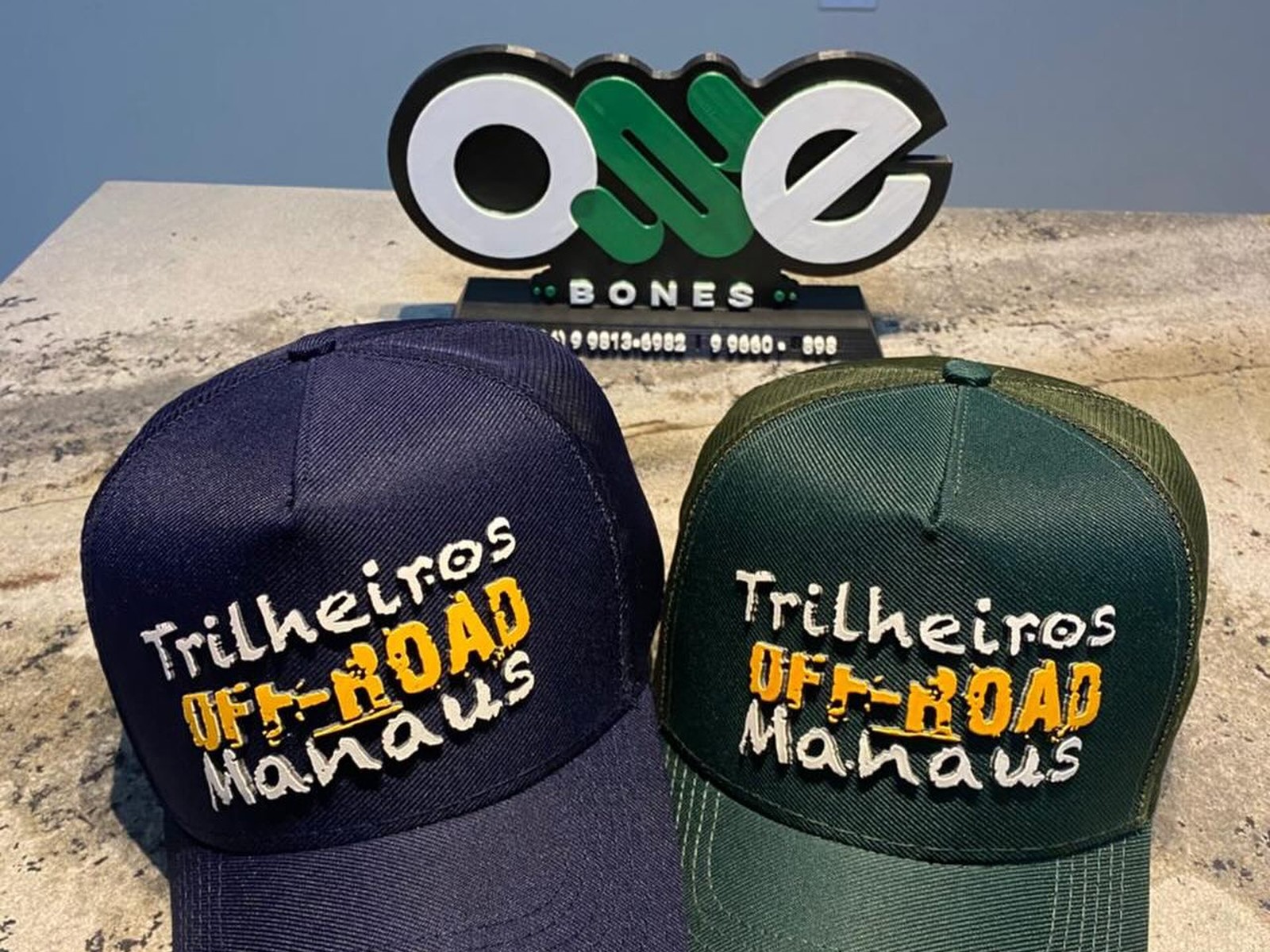 Dois bonés personalizados com bordado sobre balcão da Oxe Bonés